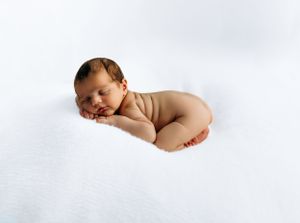 A sleeping newborn baby curled up peacefully on a soft white background.
Rashinphotography-Nova photographer- DMV DC