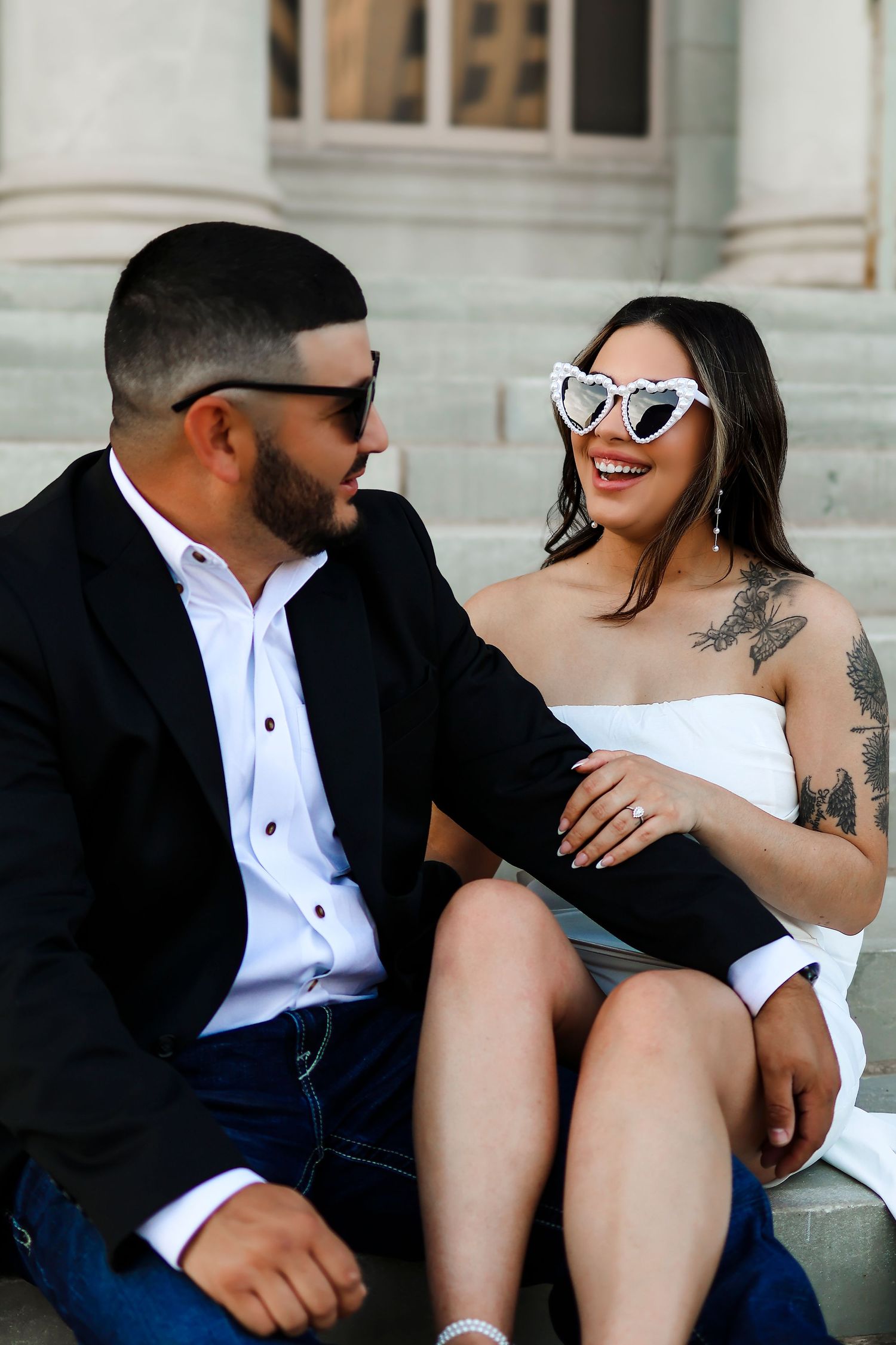 Casual couple sitting on steps sharing laughs during their engagement photoshoot.