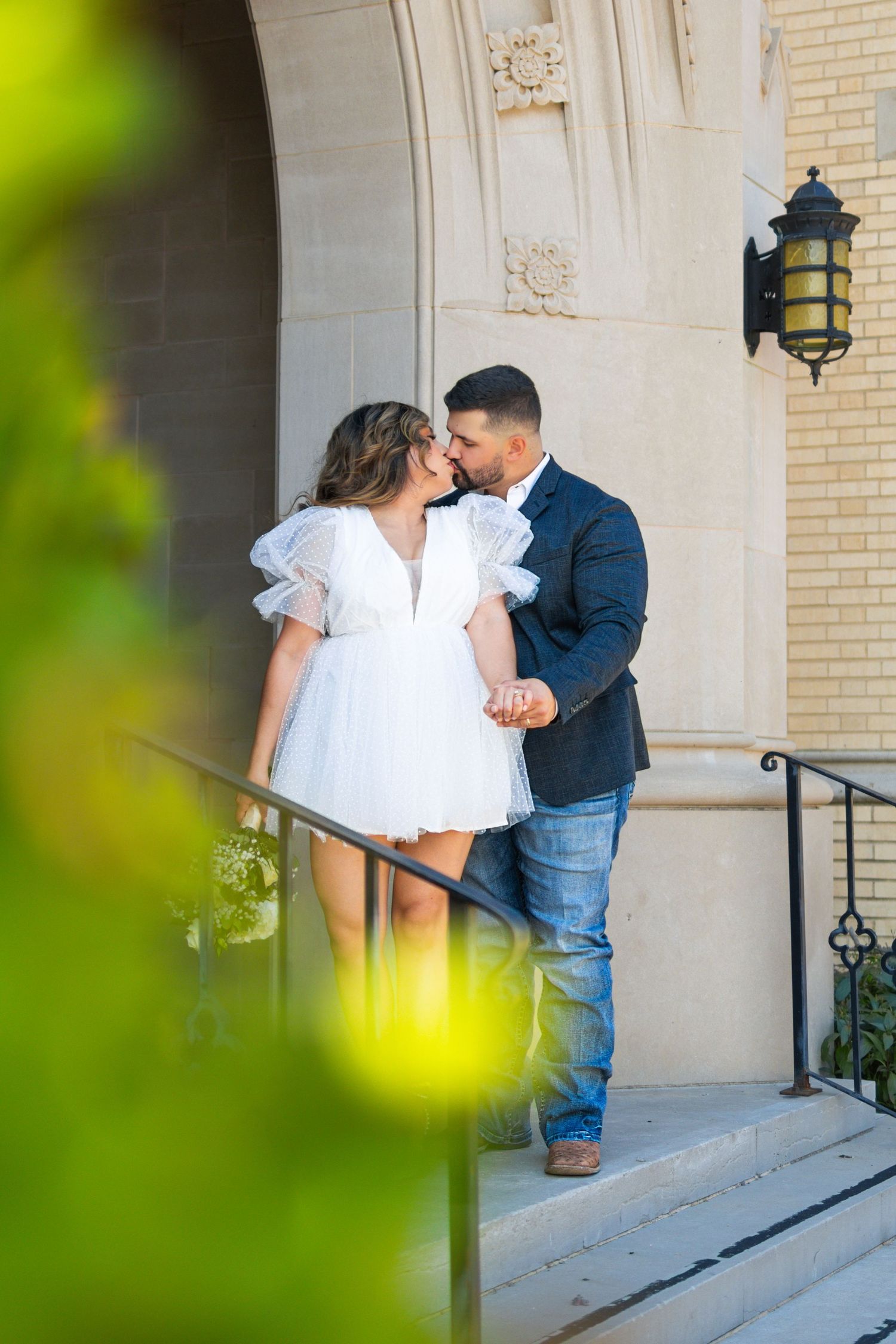 Intimate moment between couple on stone steps with architectural details visible.