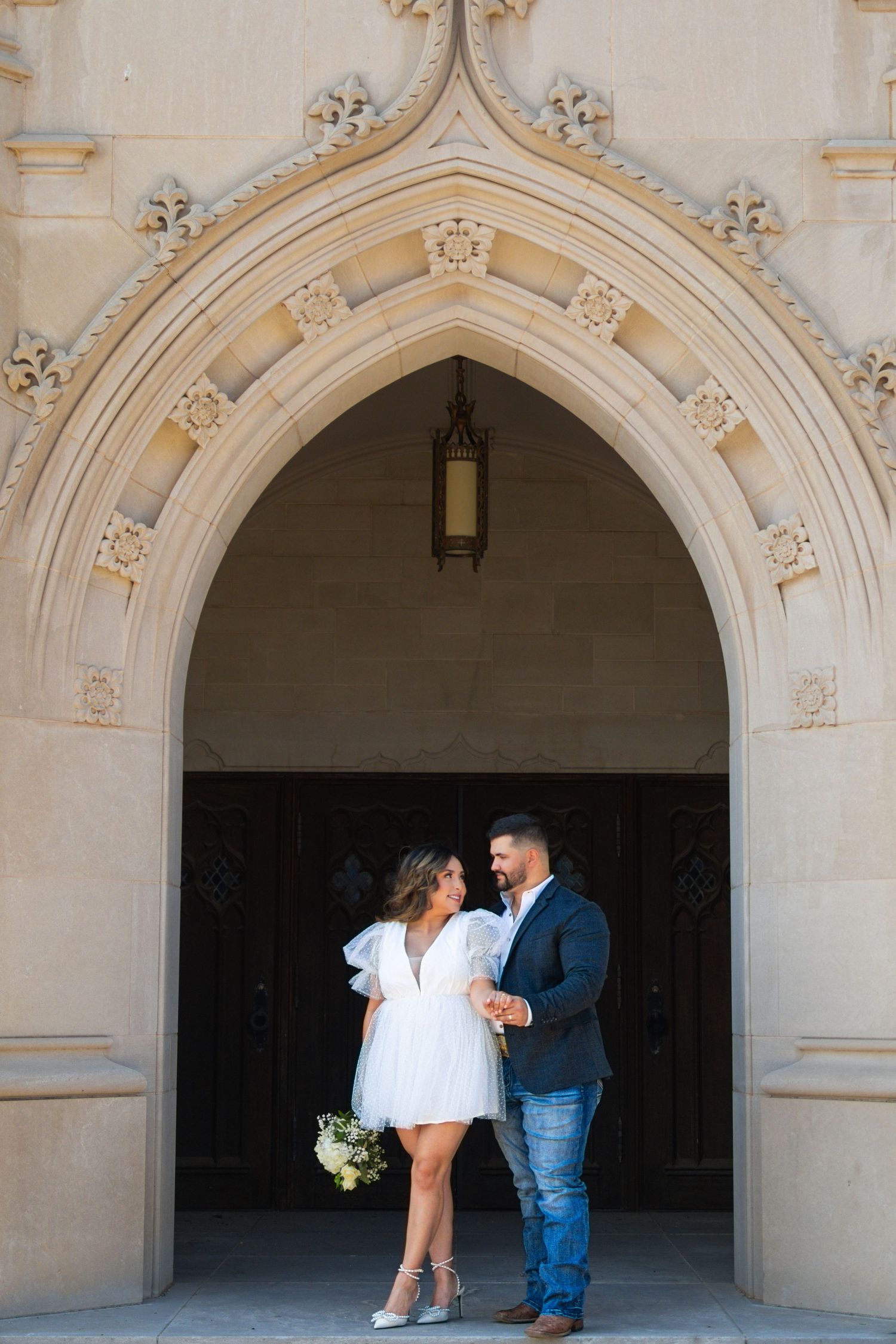 Couple stands in ornate Gothic archway entrance during photo session.