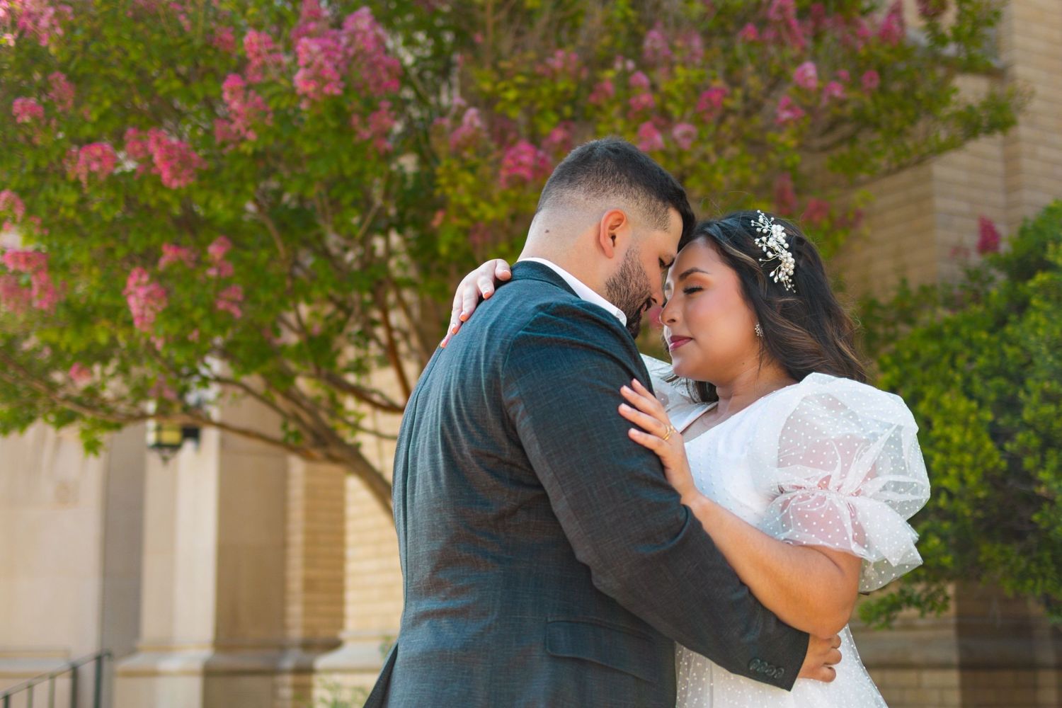 Intimate close-up moment between couple under flowering tree during photo session.