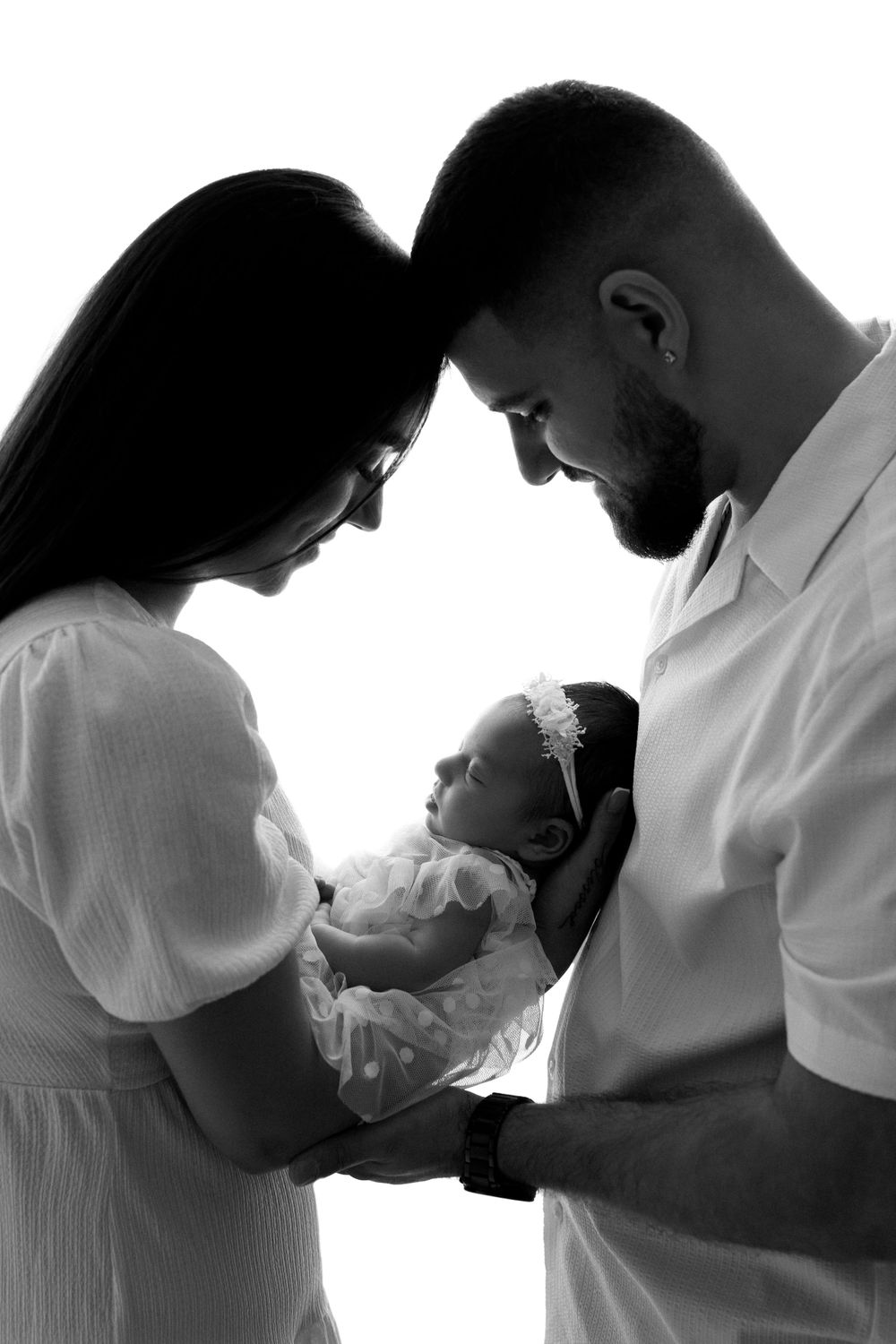Black and white silhouette portrait of family with newborn in tender moment.