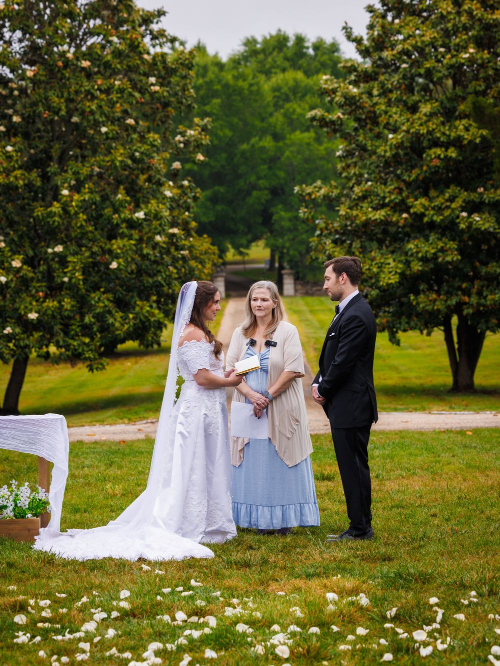Bride and groom standing together on a tree lined estate driveway during their wedding.
