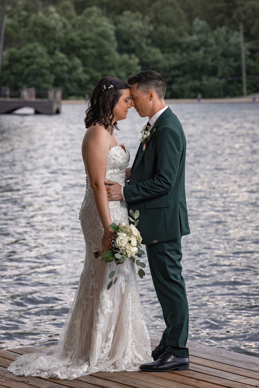 A couple by the lake on their wedding day having a romantic moment