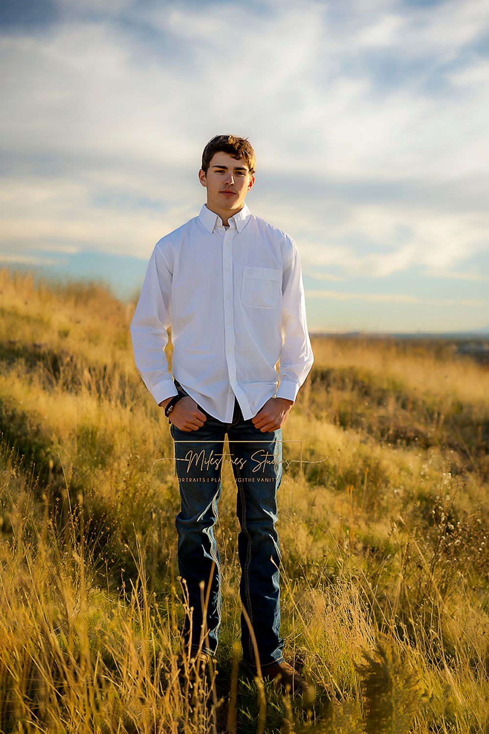 ©Milestones Portraits Boise Idaho senior photographer male wearing jeans, and a white shirt in the foothills