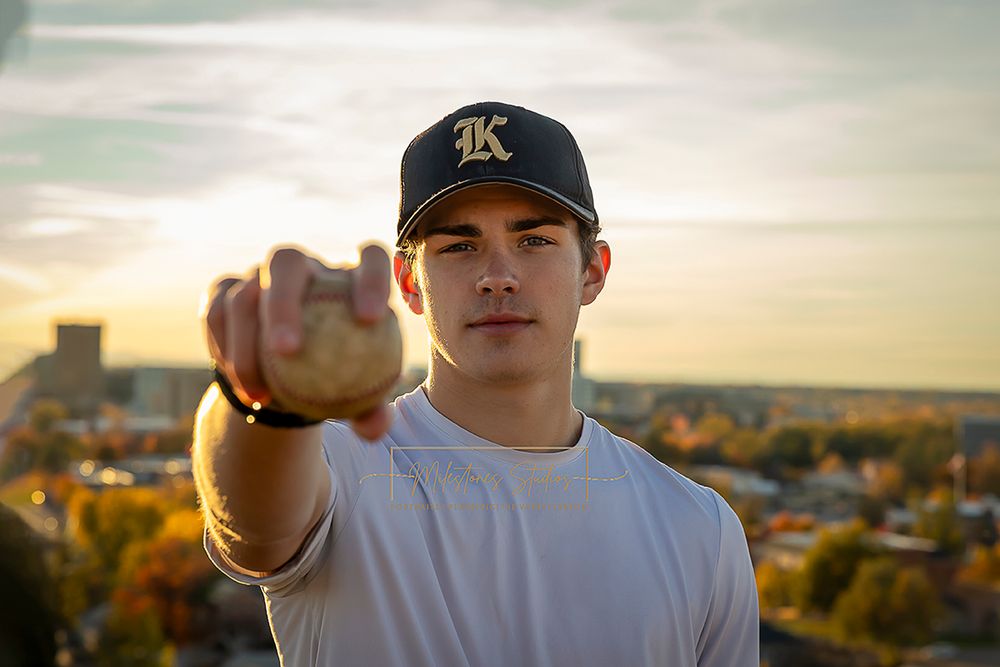 ©Milestones Portraits Boise Idaho senior photographer male wearing white tshirt, ball cap and holding a baseball in the foothills