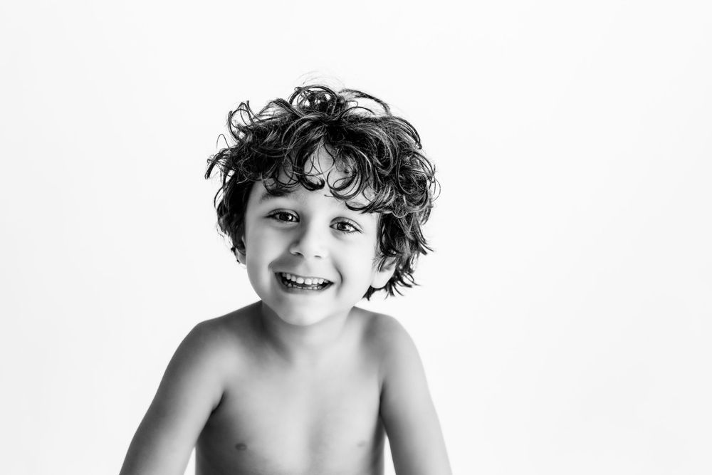 A joyful black and white portrait of a child with curly hair against a light background.
during a session in Fairfax, VA.- DMV DC
