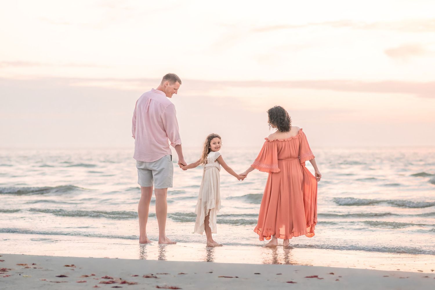 couple walking hand in hand on beach at sunset surrounded by seagulls