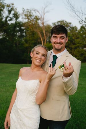Bride and groom show off their new rings, holding ring fingers to the camera.