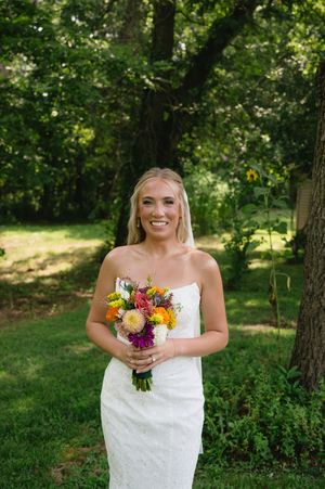 Portrait of bride holding bouquet in grove of trees.