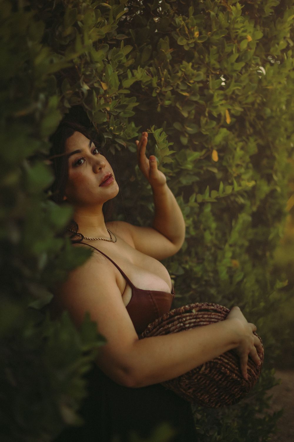 Artistic portrait photo in lush garden setting with moody lighting and romantic vintage-inspired dress and styling