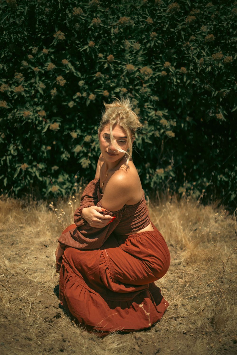 Model modeling Spanish styled clothing in a field with lush greenery in the background.