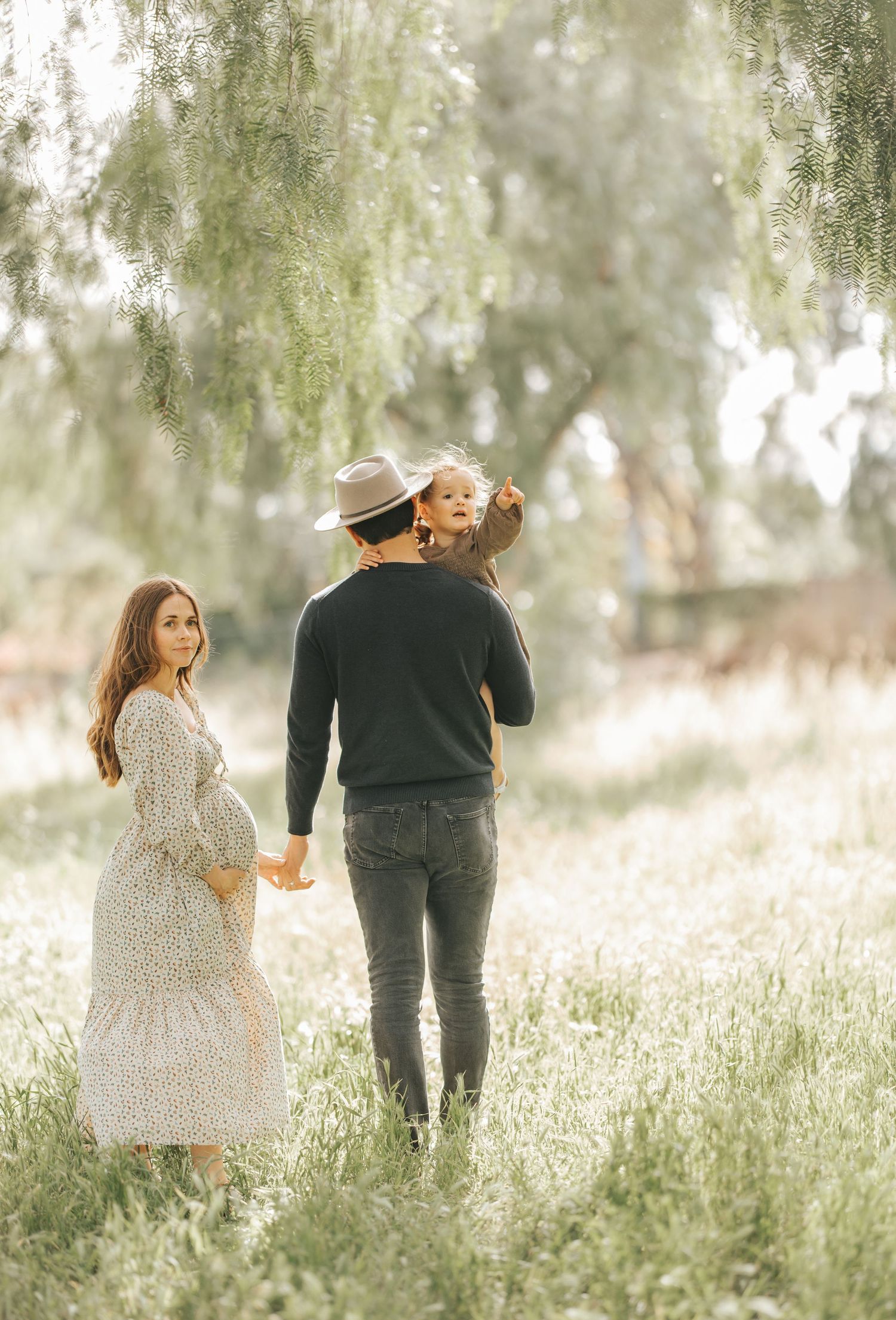 Couple walking hand in hand through a misty meadow wearing floral dress and dark casual attire.
