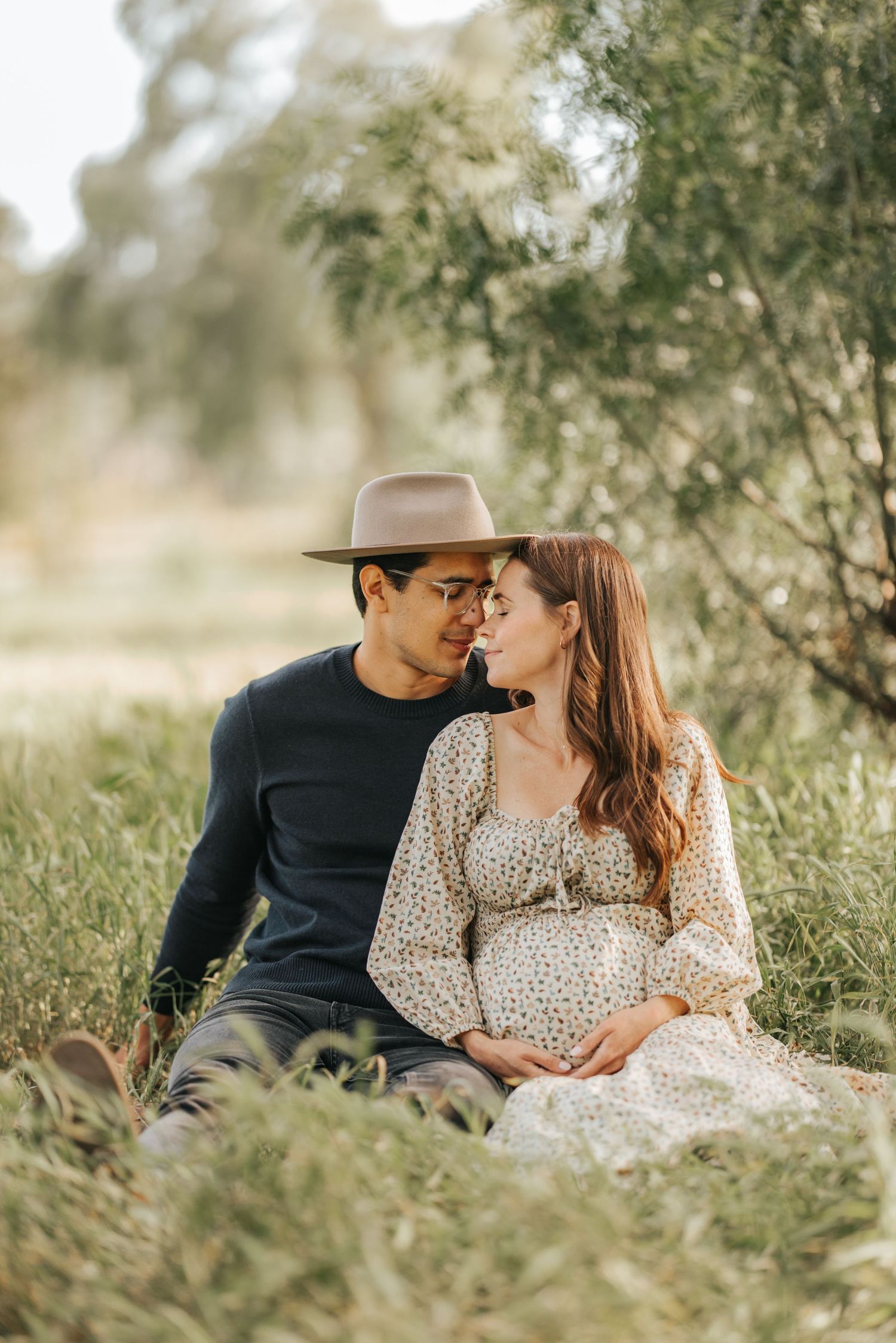 Intimate moment captured between couple during outdoor maternity session.