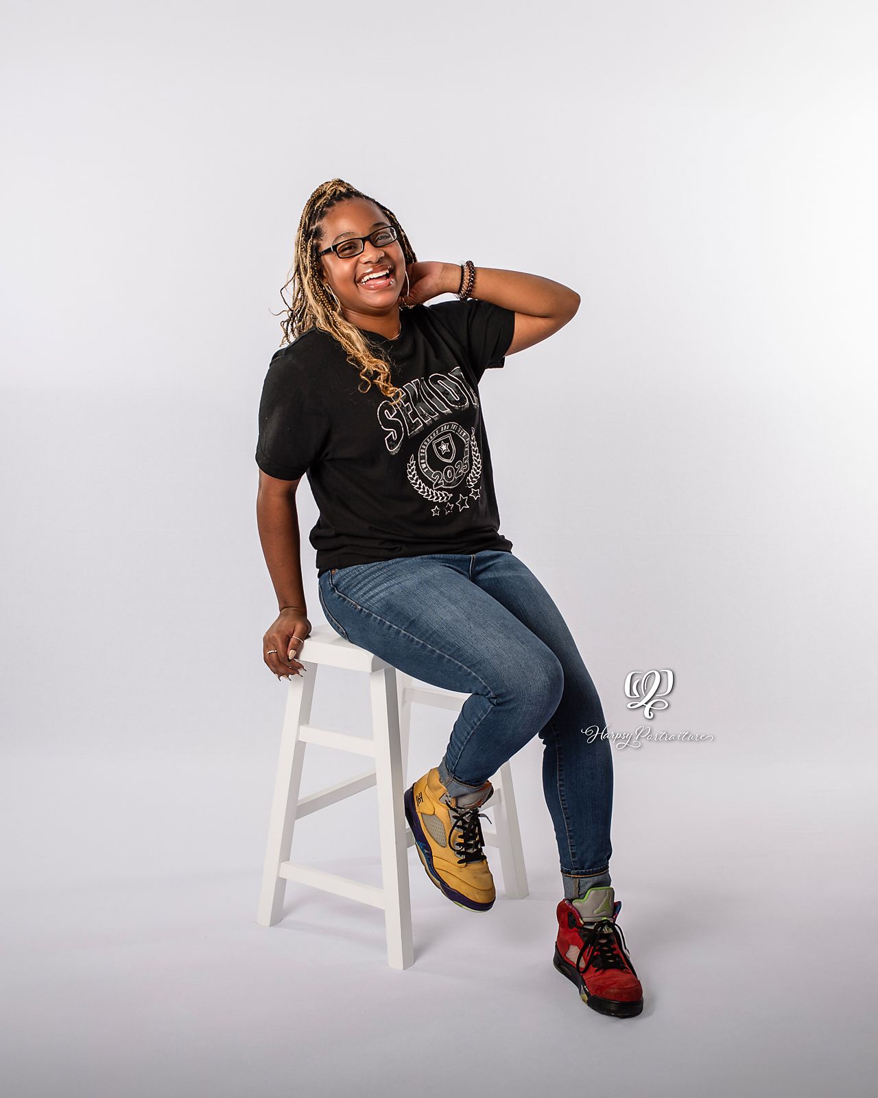 Senior student posing while laughing during senior photoshoot at indoor professional portrait studio in Lexington, SC; portrait studio