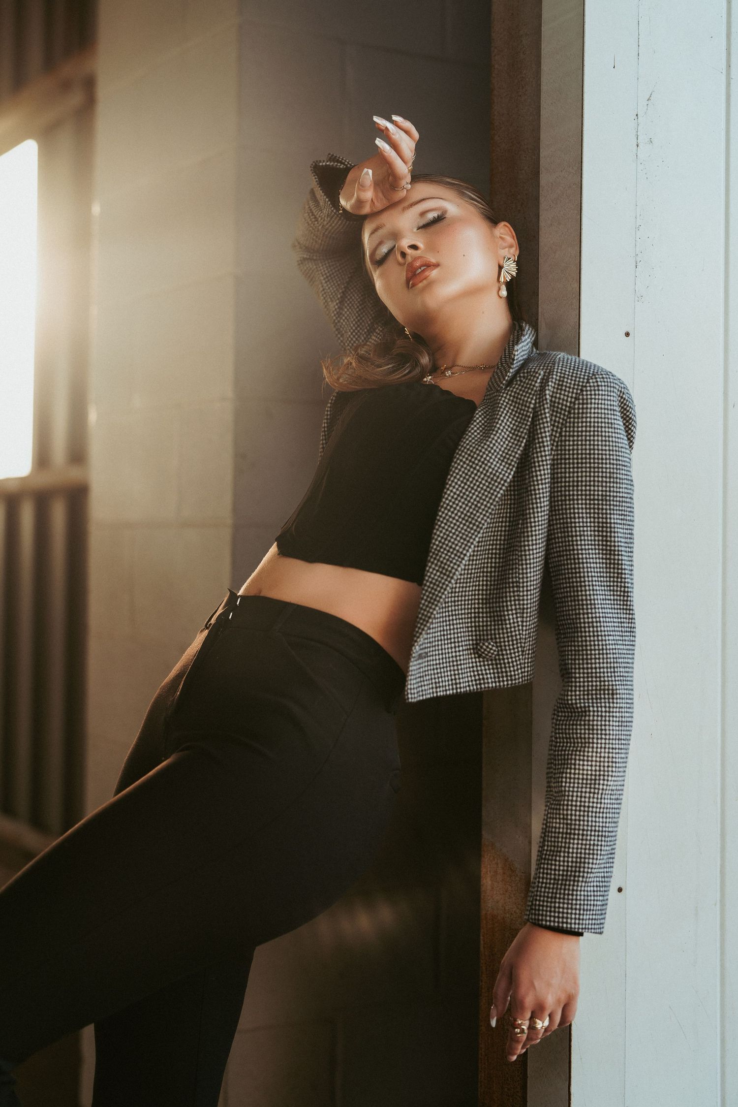 Woman in a patterned jacket in a doorway with a hand on her head