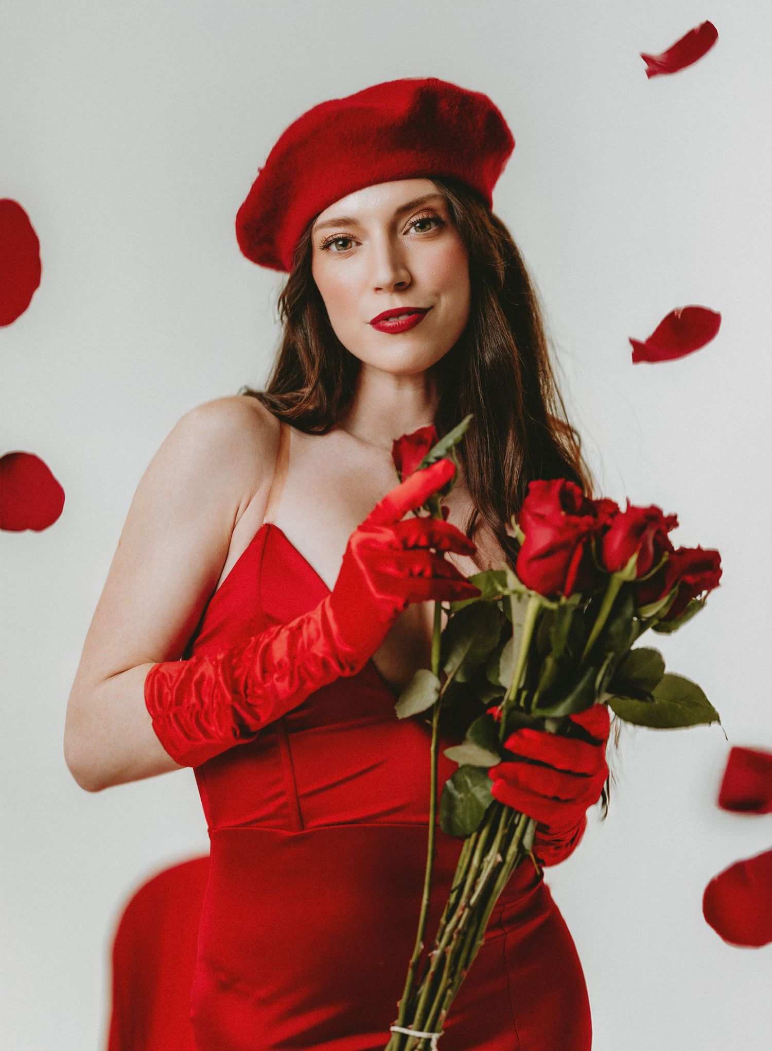 Woman in a red dress, red beret and red gloves holding roses in a studio in Northern Kentucky
