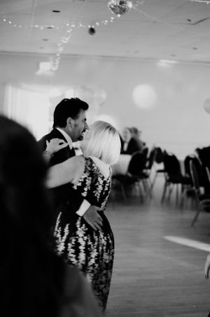 A couple dancing at a wedding reception under twinkling lights.
