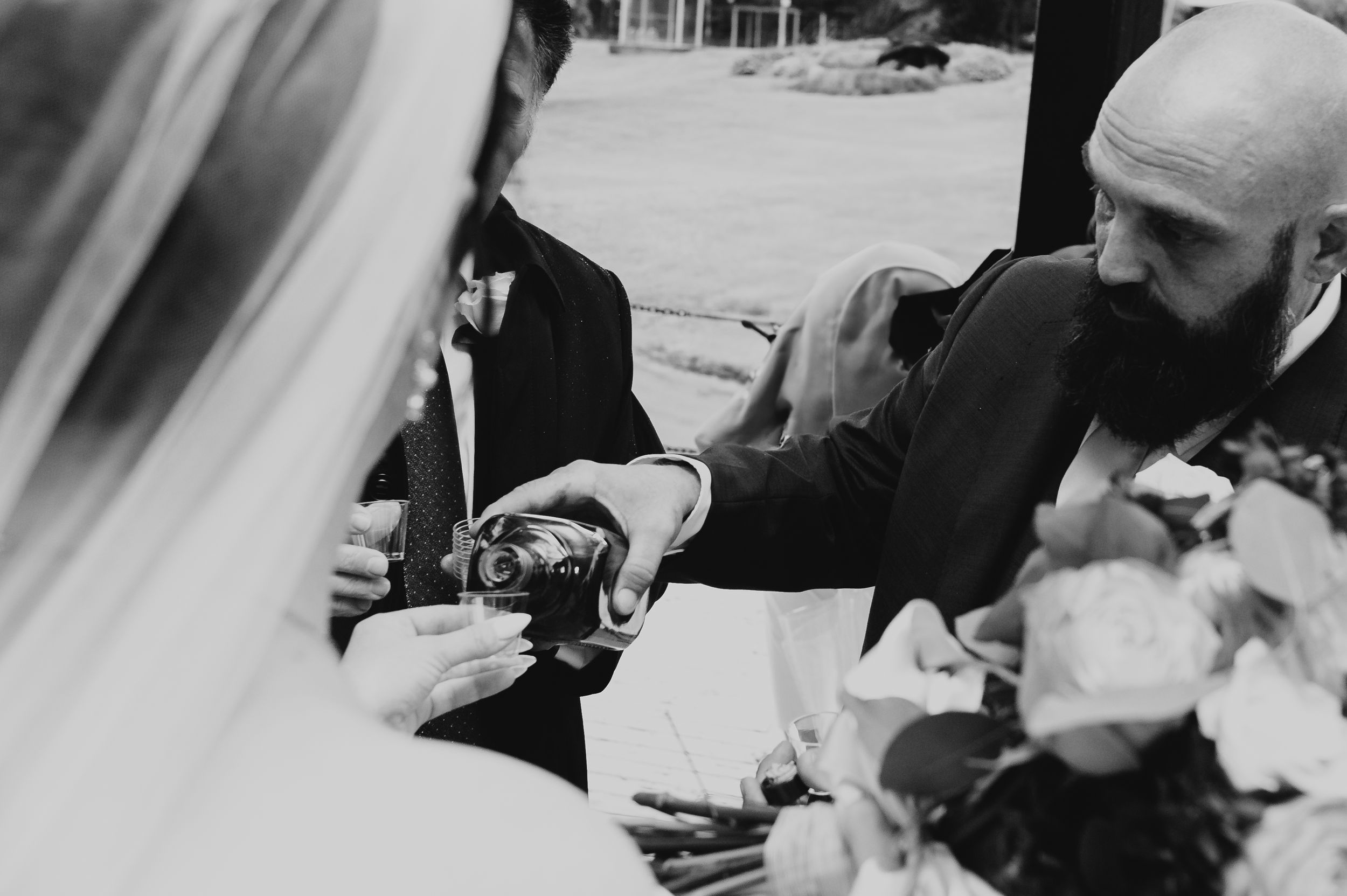 A black and white wedding detail shot of hands exchanging rings.