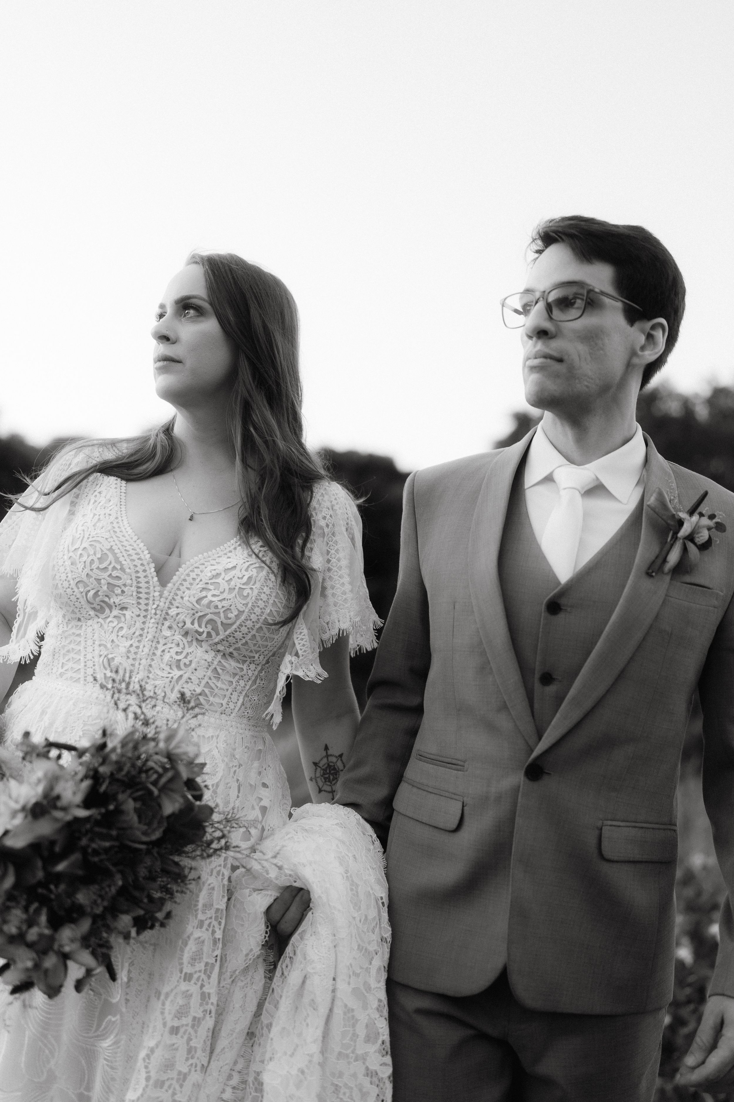 A romantic black and white portrait of newlyweds in white dress and gray suit outdoors.