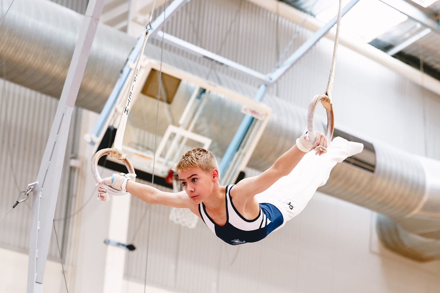 Athlete performing routine on gymnastic rings in indoor training facility.