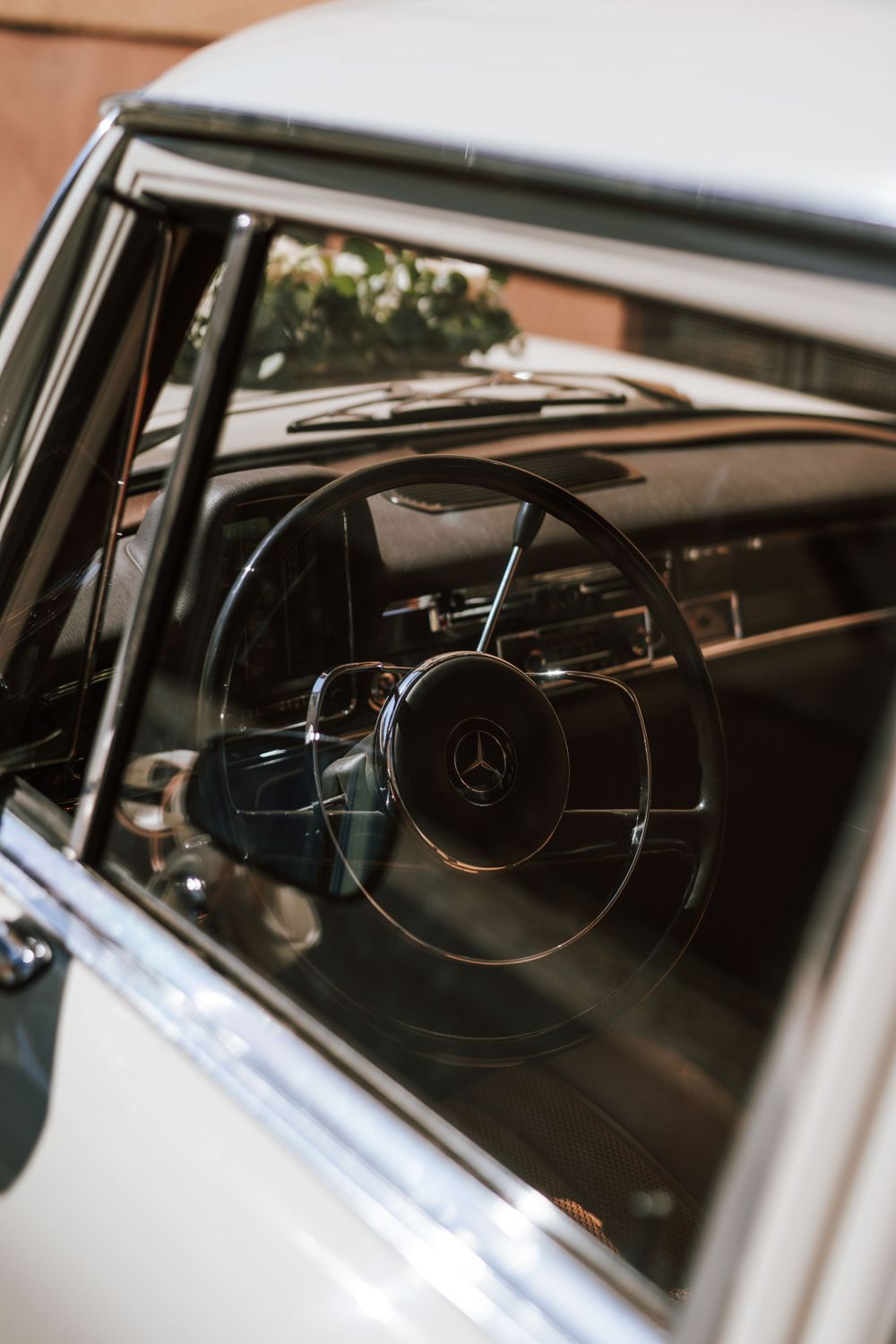 Interior dashboard view of a classic Mercedes-Benz car showing vintage steering wheel and gauges.