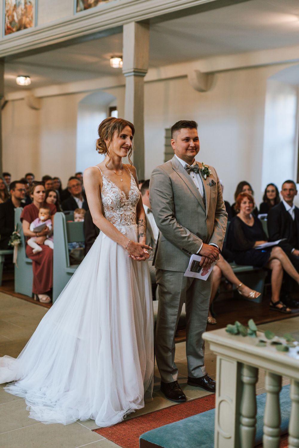 A couple stands at the altar during their wedding ceremony in a traditional church setting.