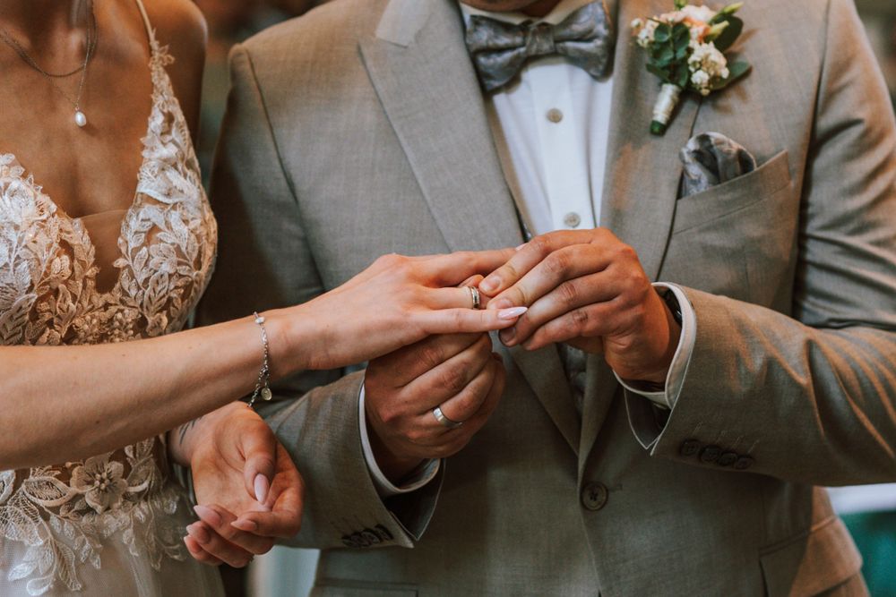 Close-up of hands exchanging wedding rings during ceremony.