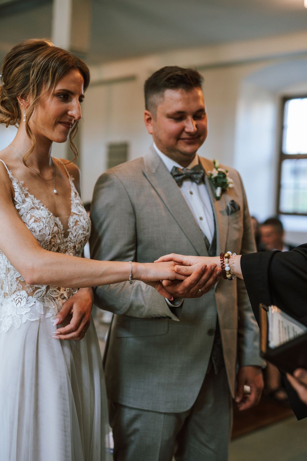 Wedding ceremony ring exchange moment in a traditional church setting.