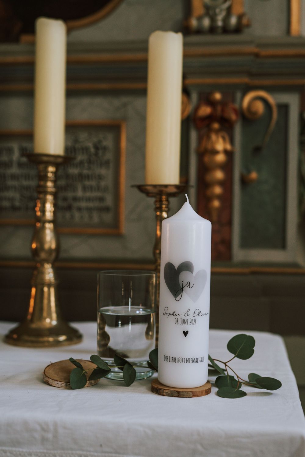 White candles and greenery decorate a table with elegant wedding reception details.