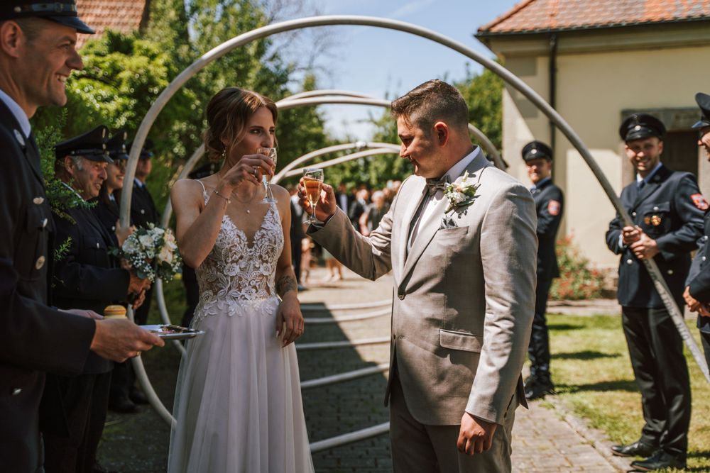 Wedding ceremony under decorative arch in sunny garden setting.