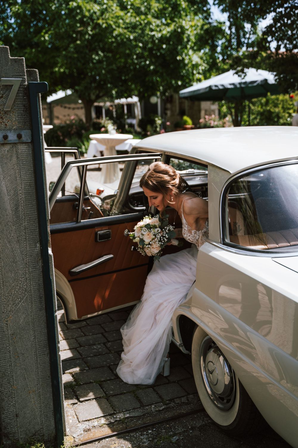 A classic white vintage car serves as elegant wedding transportation.