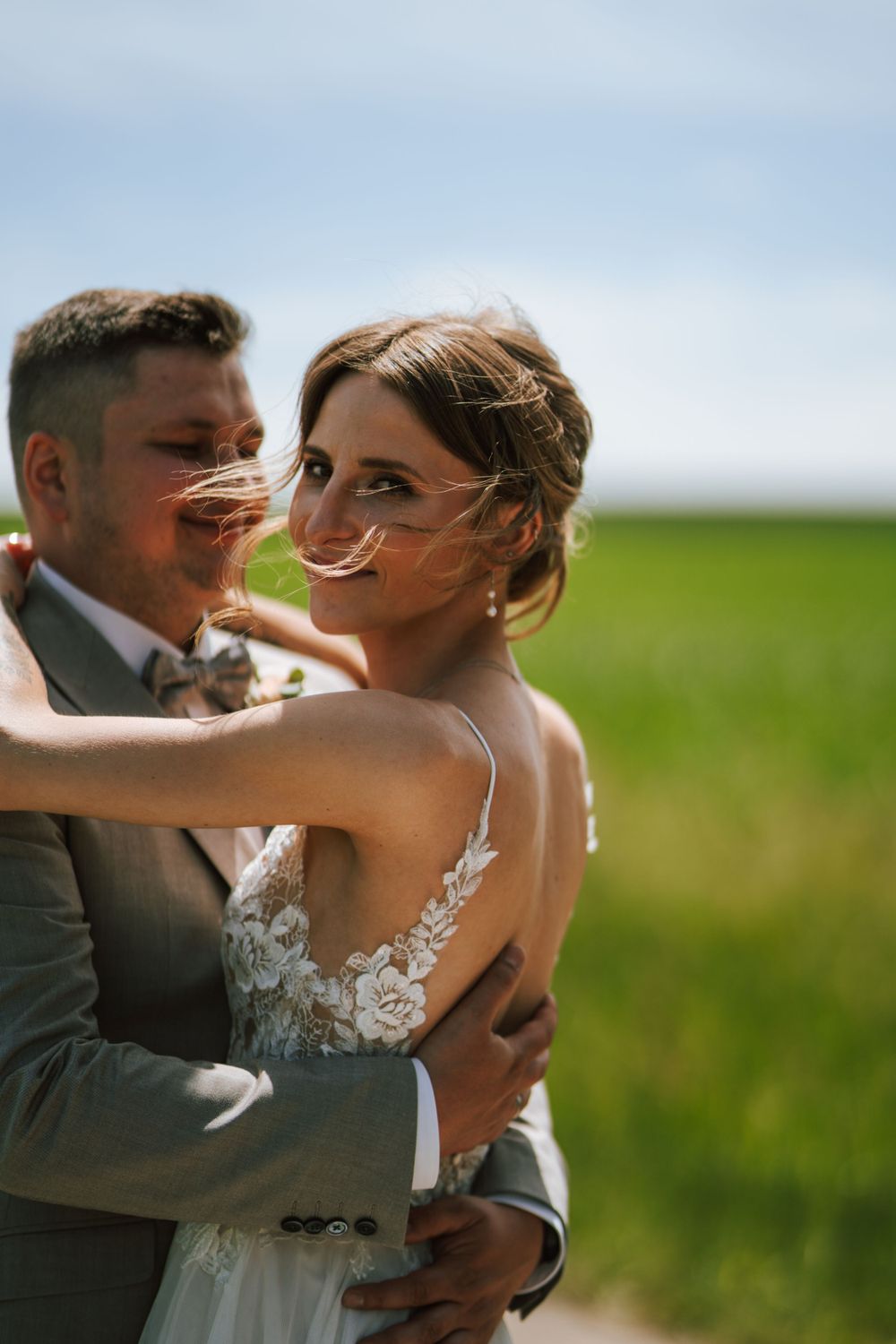 Candid moment of newlyweds sharing laughter during their countryside wedding photoshoot.