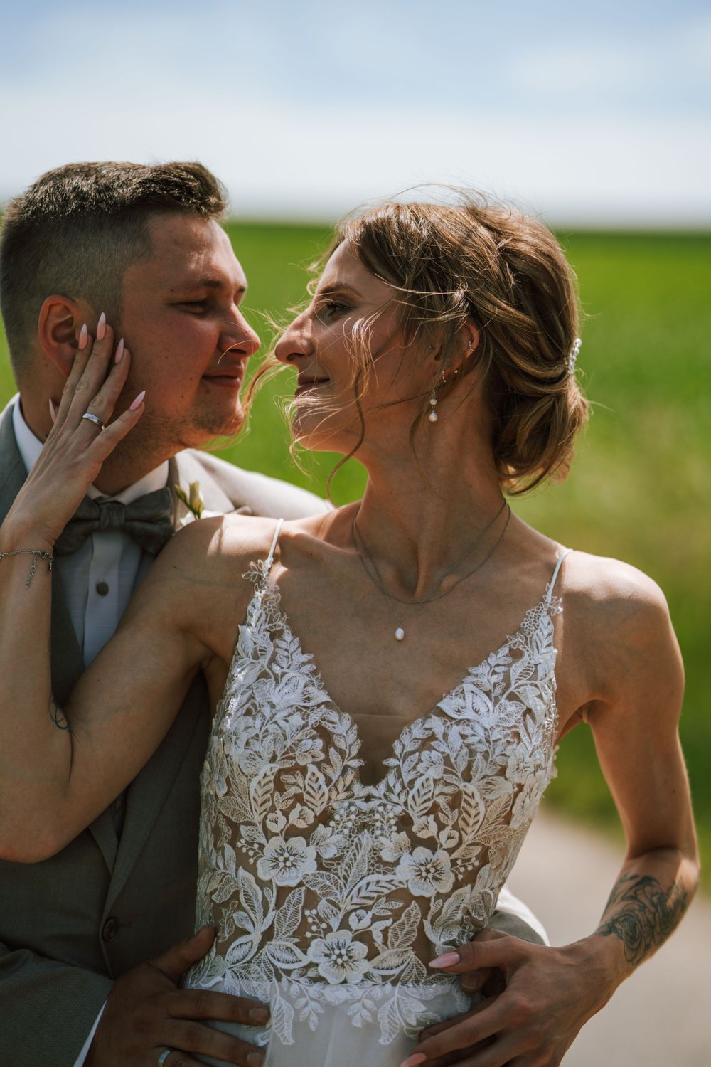 Candid wedding portrait showing genuine emotion between couple in countryside setting.