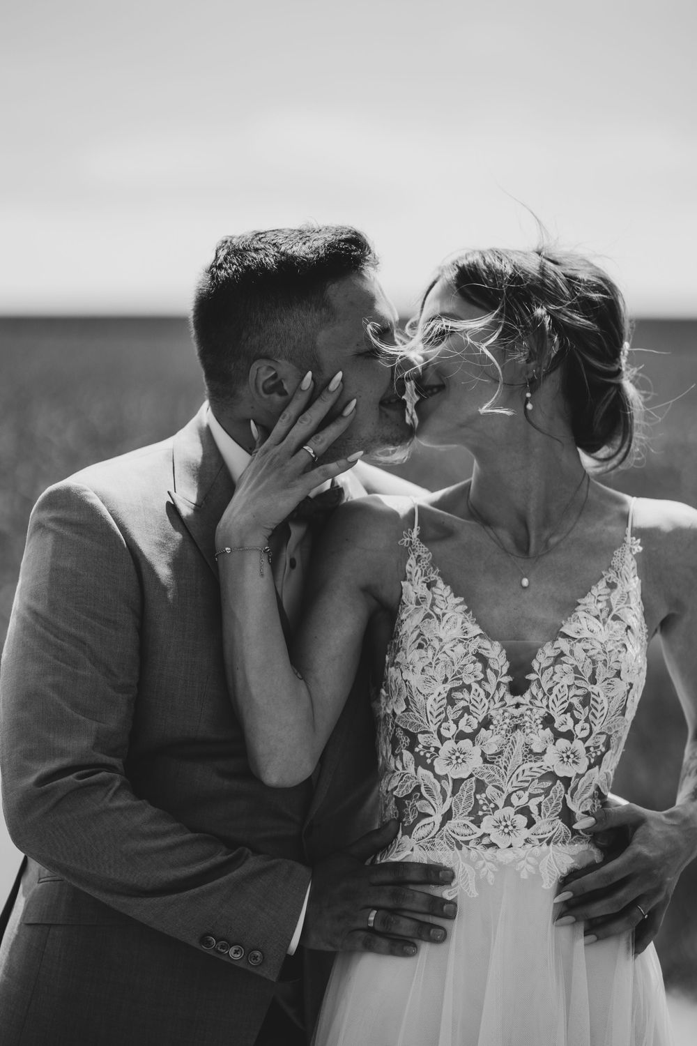 Black and white wedding portrait capturing intimate moment between newlyweds in natural setting.