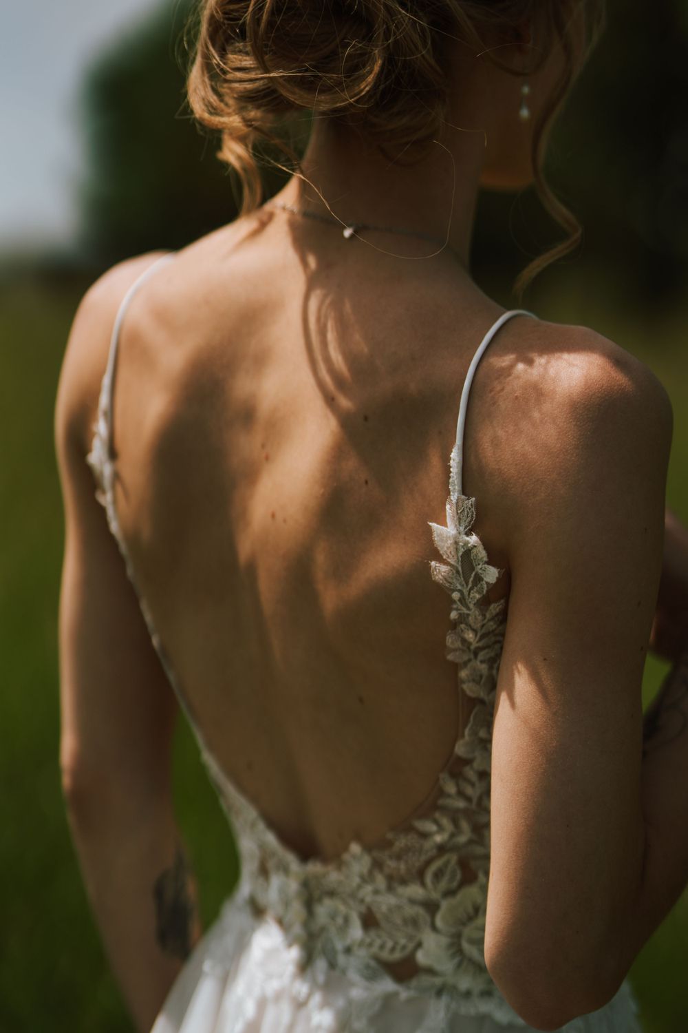 Back view of elegant white lace wedding dress with intricate strap details.