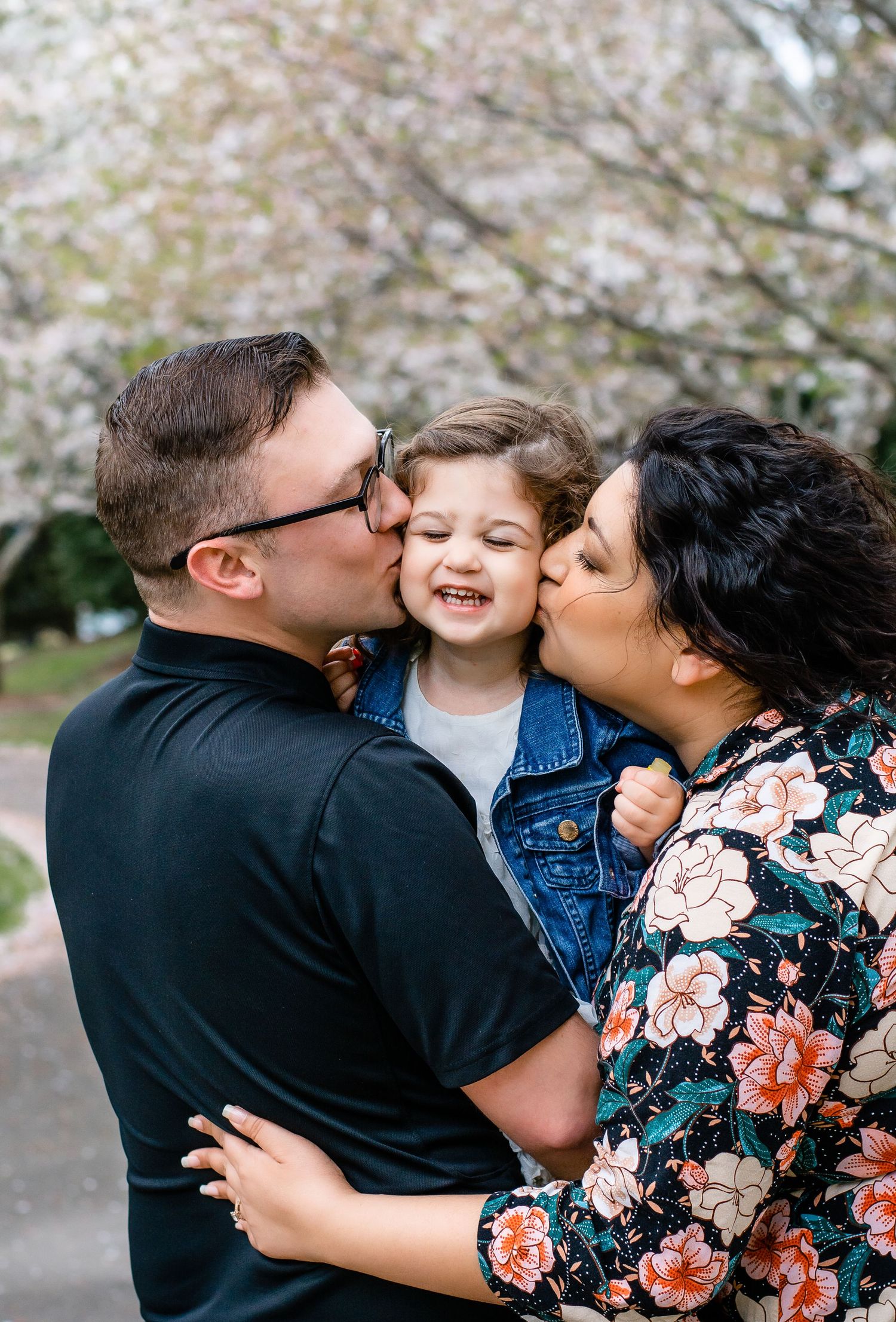 Intimate family moment captured under blooming cherry blossoms.