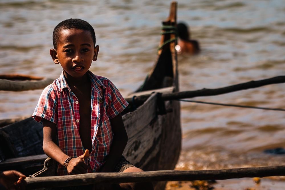 A small wooden boat on brown river waters.
