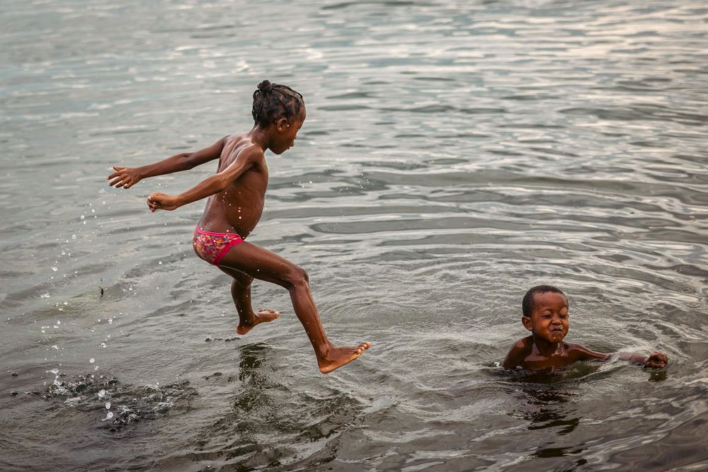 Children playing and splashing in ocean water during sunset.
