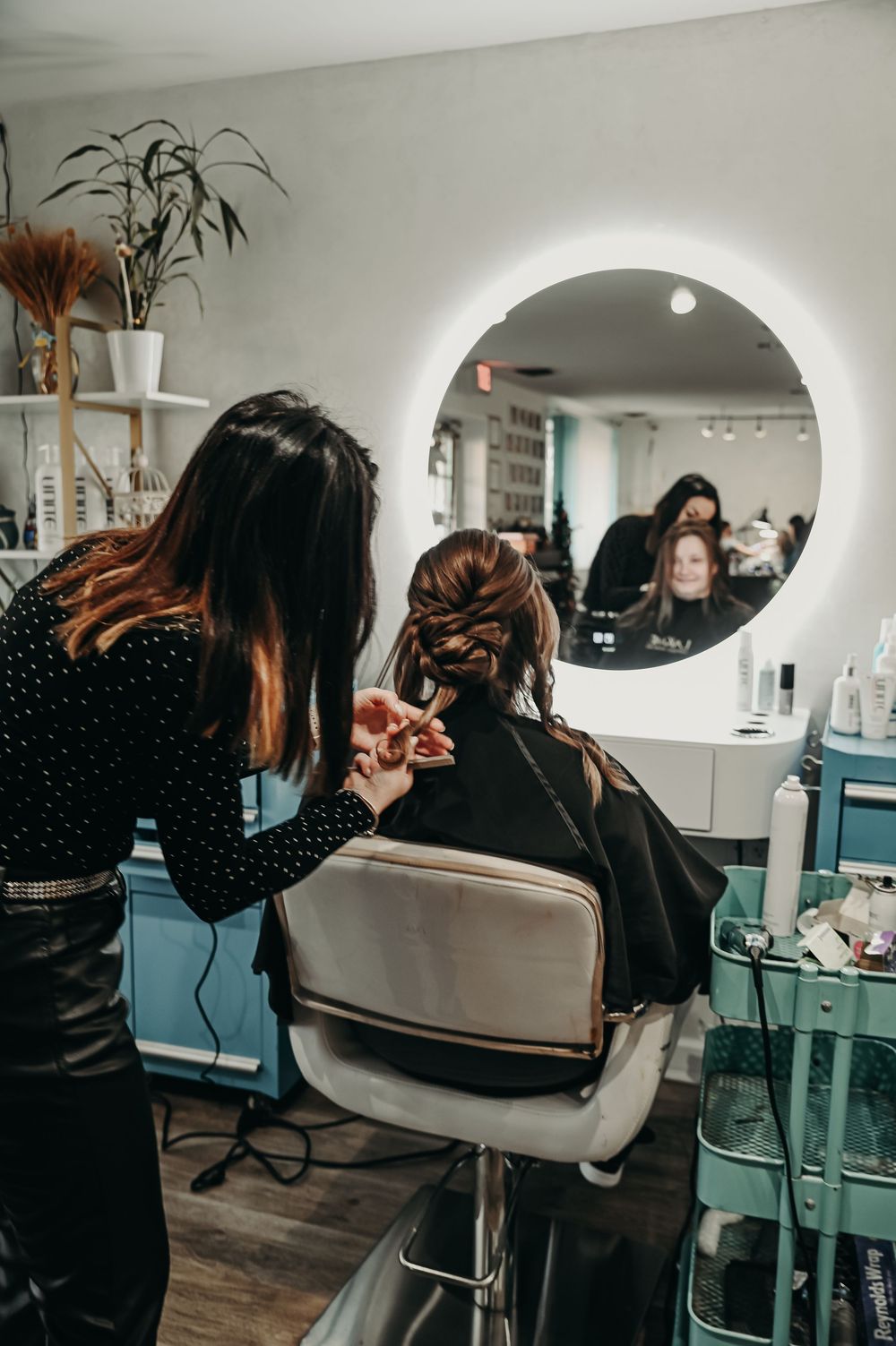 Professional hairstylist working on client's hair in a contemporary salon setting.