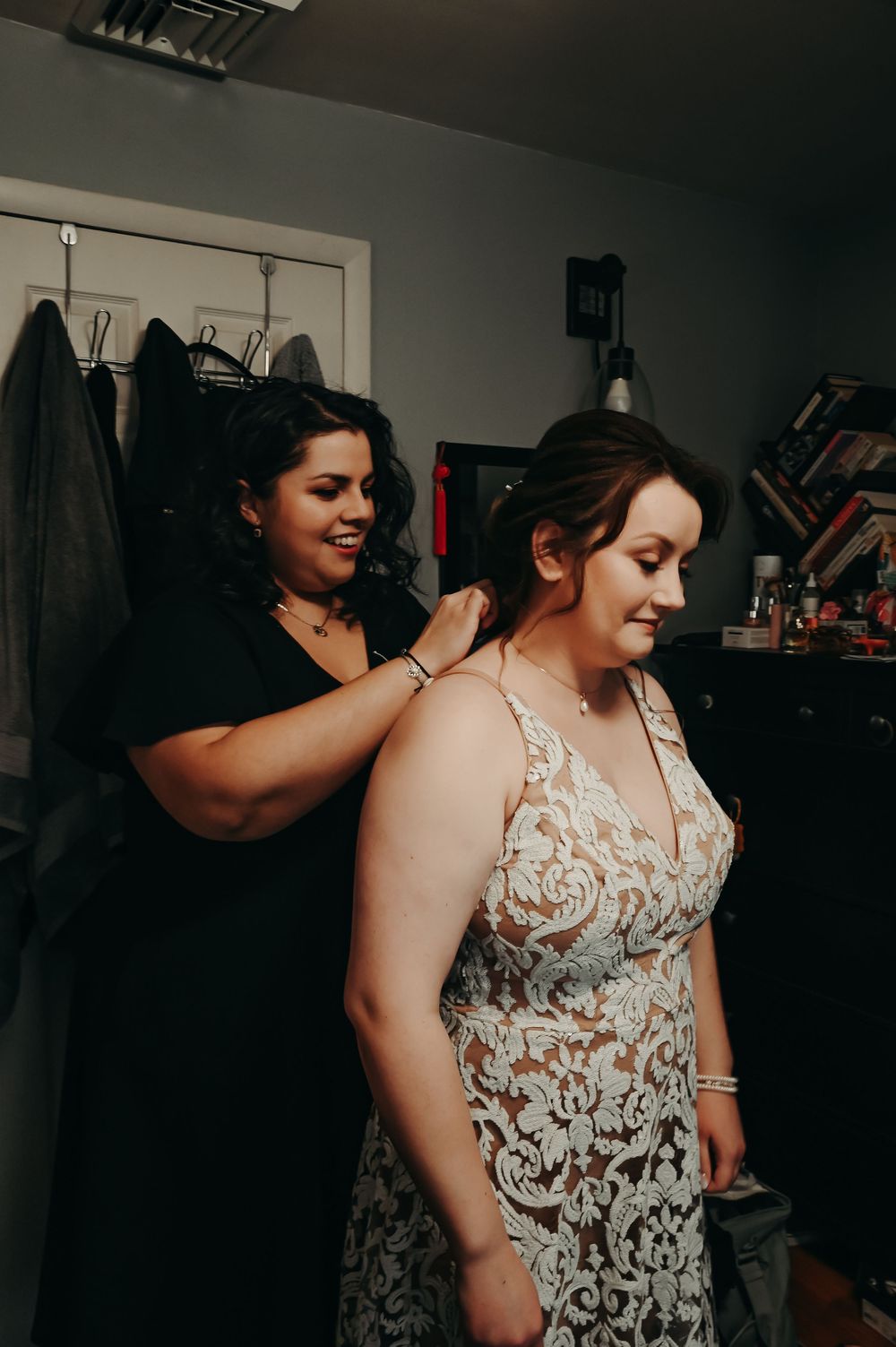 Someone helping with wedding preparations in a dimly lit dressing room.