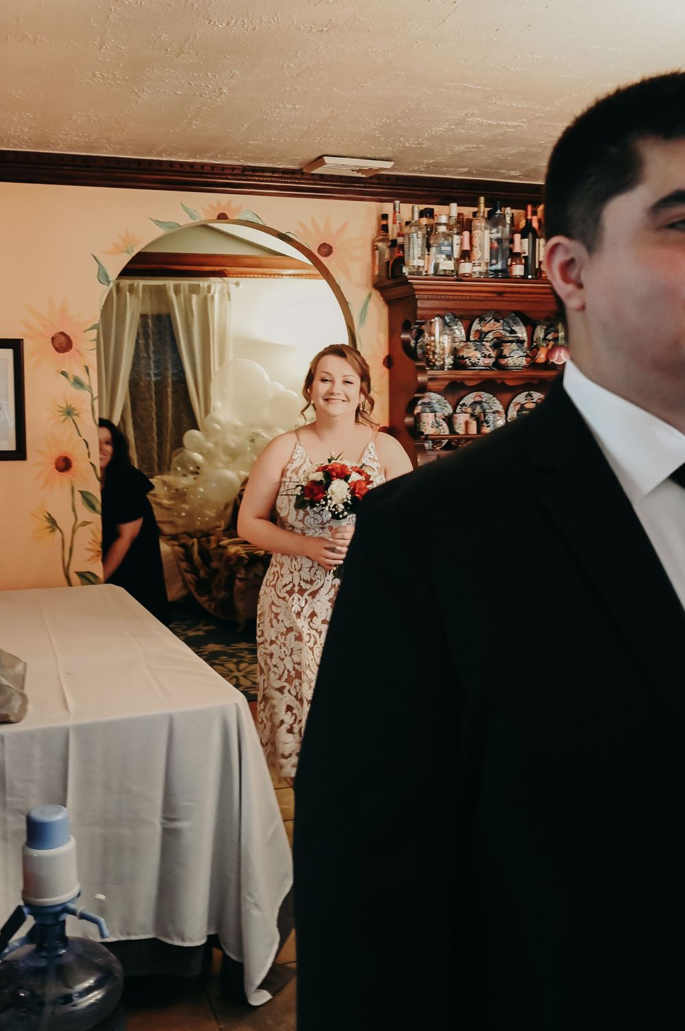 A wedding scene with formal attire and floral decorations in a warm-toned room.