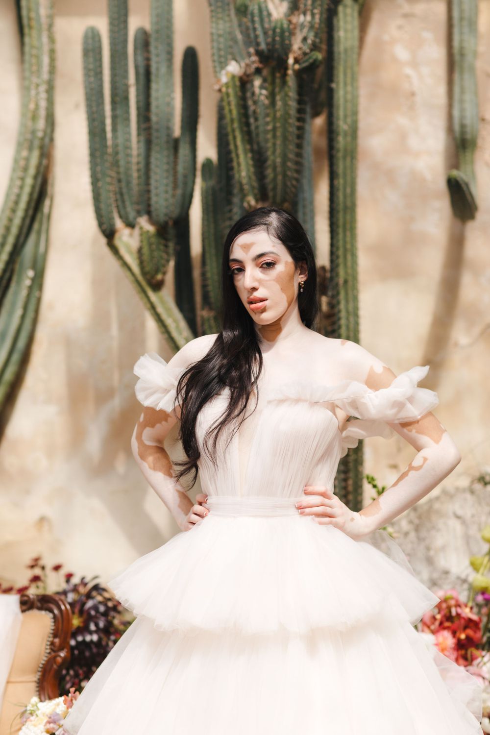 Bride in dramatic tulle ballgown poses against desert backdrop with tall cacti.