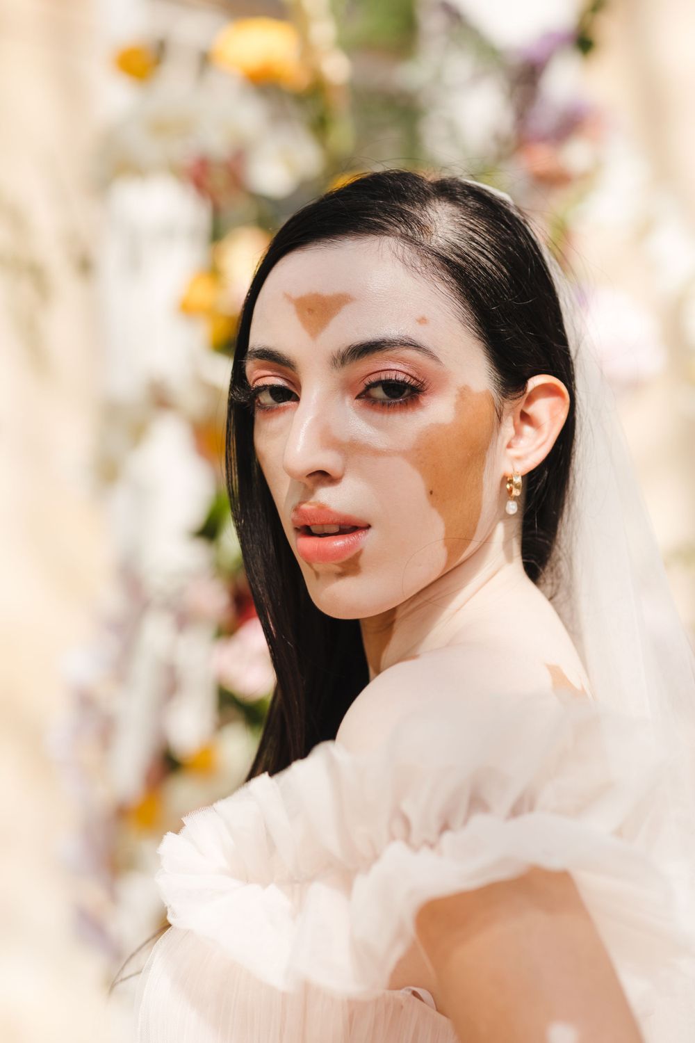 Close-up bridal beauty portrait with natural makeup and floral background.
