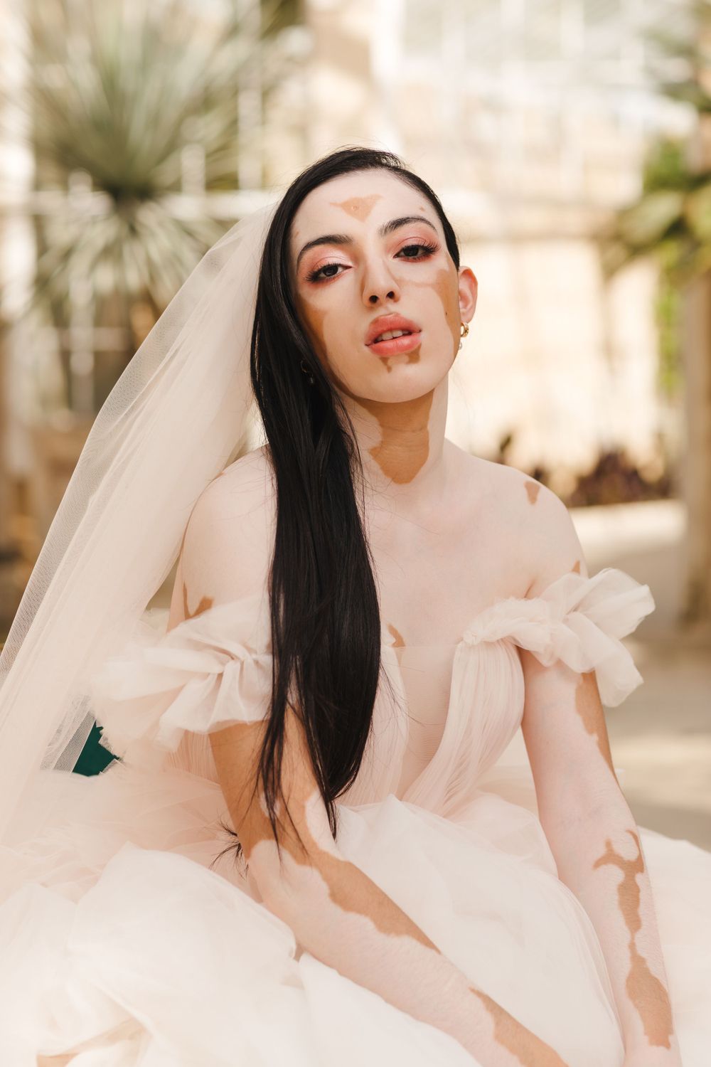Sun-lit bridal portrait featuring soft makeup and flowing white dress.
