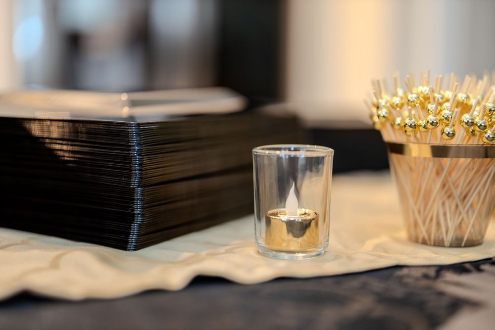 Elegant party setup with black napkins, glass votives and golden crown decorations on a table.