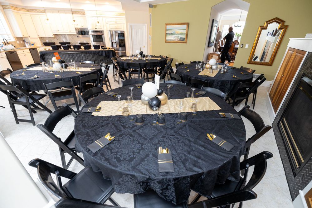 An event space set up with round tables covered in black tablecloths and matching chairs.