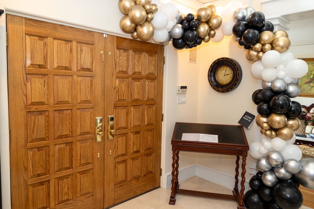 Wooden double doors decorated with black and gold balloon arch for a celebration.