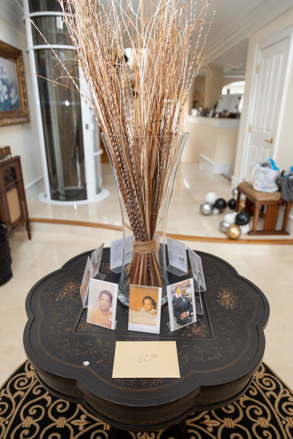 Dried wheat stalks in vase with polaroid photos displayed on black decorative table.