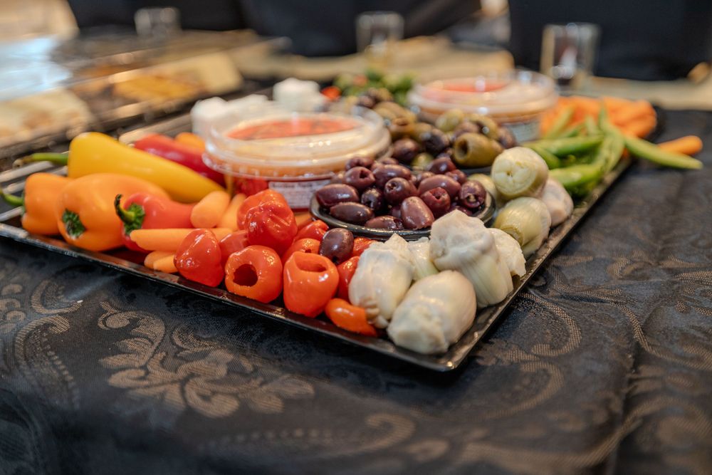 Fresh colorful vegetables and appetizers arranged on a dark serving platter.